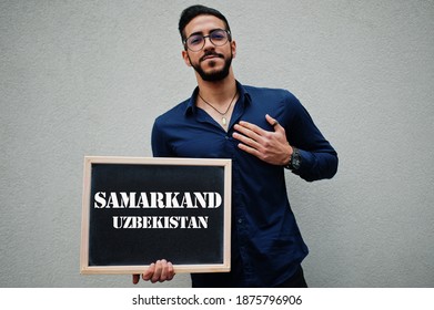 Arab man wear blue shirt and eyeglasses hold board with Samarkand Uzbekistan inscription. Largest cities in islamic world concept.