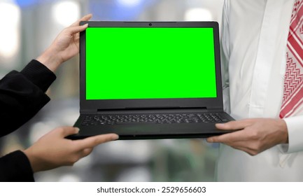 Arab man and women holding laptop screen chroma key green screen  - Powered by Shutterstock