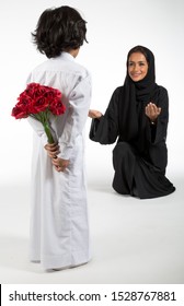 Arab Middle Eastern Saudi Boy With Flowers Behind His Back, Surprising His Mom On Mother’s Day, On White Isolated Background, Ready For Cutout And Design Purposes.