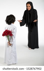 Arab Middle Eastern Saudi Boy With Flowers Behind His Back, Surprising His Mom On Mother’s Day, On White Isolated Background, Ready For Cutout And Design Purposes.