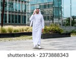 Arab middle-eastern man wearing emirati kandora traditional clothing in the city - Arabian muslim businessman strolling in urban business centre.