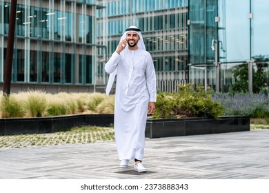 Arab middle-eastern man wearing emirati kandora traditional clothing in the city - Arabian muslim businessman strolling in urban business centre. - Powered by Shutterstock