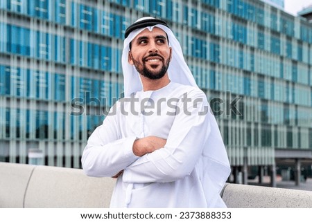 Arab middle-eastern man wearing emirati kandora traditional clothing in the city - Arabian muslim businessman strolling in urban business centre.