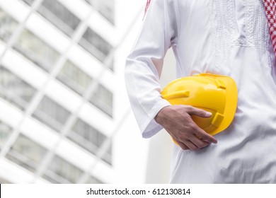 Arab Muslim Engineer Uniform And Worker Checking Construction Drawing At Construction Site. And Space For Your Text