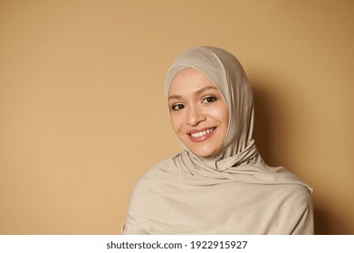 Arab Muslim Woman Wearing Hijab Looking At Camera While Posing With A Beautiful Toothy Smile On A Beige Background With Copy Space. Strict Formal Outfit And Elegant Appearance. Islamic Fashion.