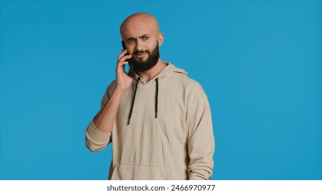 Arab person answering phone call in front of camera, talking to his friends on remote chat with smartphone. Young adult using mobile phone communication to discuss with people. Camera 1. - Powered by Shutterstock