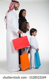 Arab Saudi family at the mall with colored shopping bags, on white isolated background, ready for cutout and design purposes.