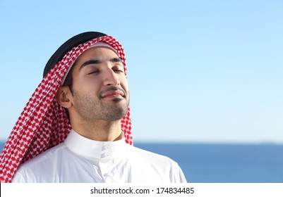 Arab Saudi Man Breathing Deep Fresh Air In The Beach With The Ocean And Horizon In The Background          