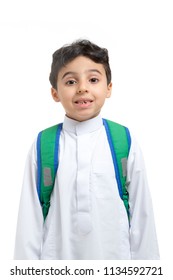 Arab school boy closeup on face with a smile and broken tooth, wearing white traditional Saudi Thobe, back pack and sneakers, raising his hands on white isolated background