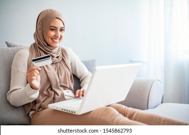 Arab Woman Making Online Purchase On Laptop. Portrait Of Happy Woman Purchasing Product Via Online Shopping. Pay Using Credit Card. Muslim Woman Online Shopping