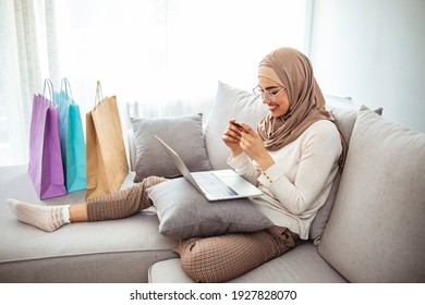 Arab Woman Making Online Purchase On Laptop. Portrait Of Happy Woman Purchasing Product Via Online Shopping. Pay Using Credit Card. Muslim Woman Online Shopping