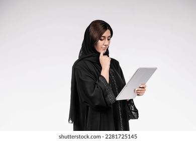 Arab woman using tablet or laptop wearing Abaya. - Powered by Shutterstock