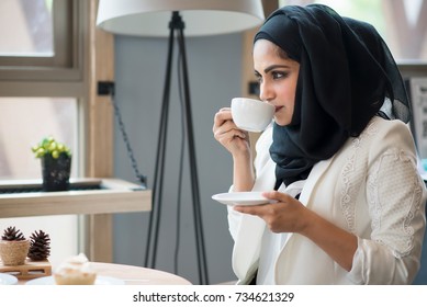 Arab Women In Hijab Holding And Drinking Coffee Cup Sitting In The Coffee Shop.