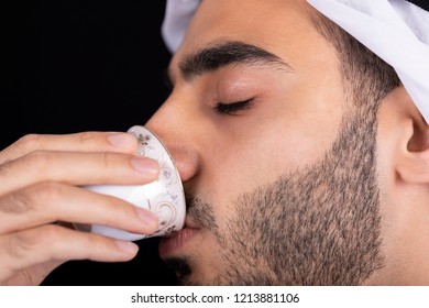 Arab Young Man Enjoying While Drinking Arabic Coffee Or Tea Isolated On Black 