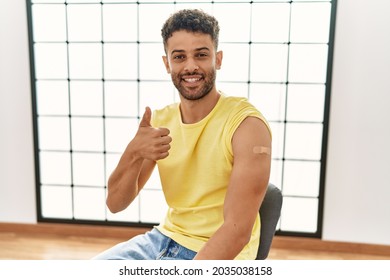 Arab Young Man Getting Vaccine Showing Arm With Band Aid Smiling Happy And Positive, Thumb Up Doing Excellent And Approval Sign 