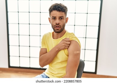 Arab Young Man Getting Vaccine Showing Arm With Band Aid Scared And Amazed With Open Mouth For Surprise, Disbelief Face 