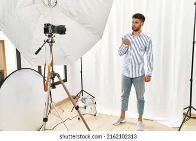 Arab Young Man Posing As Model At Photography Studio Pointing Aside Worried And Nervous With Forefinger, Concerned And Surprised Expression 