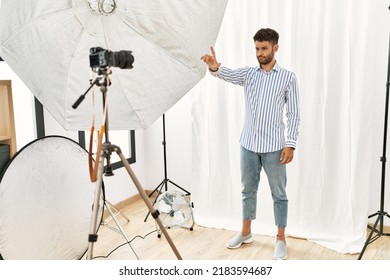 Arab Young Man Posing As Model At Photography Studio Pointing With Finger Up And Angry Expression, Showing No Gesture 