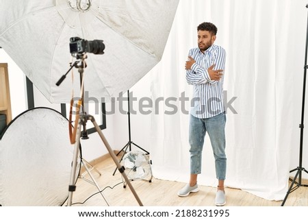 Arab young man posing as model at photography studio shaking and freezing for winter cold with sad and shock expression on face 