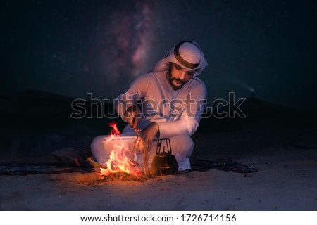 Arab young man sitting around bonfire in the desert, Arabic comping, middle east tourism concept.