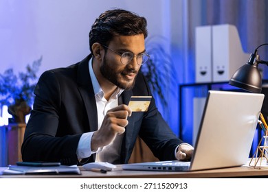 Arabian businessman programmer software developer working making online purchase payment shopping with credit bank card and use laptop at home office desk with laptop. Indian freelancer business man