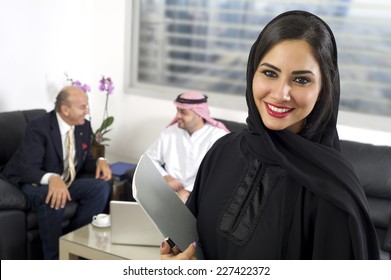 Arabian Businesswoman in office with Businesspeople meeting in the background, Arabian woman wearing Hijab in office with her colleagues in background