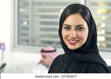 Arabian Businesswoman wearing hijab with her boss in background, Arabian businesspeople in office