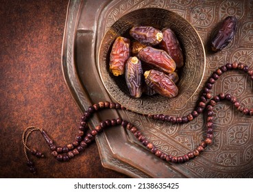 Arabian Dates In An Antique Metal Bowl With Islamic Prayer Beads. Ramadan Kareem- Muslim Festival Objects And Background.
