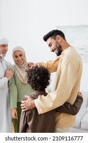 arabian father and son embracing near happy interracial muslim family