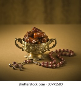 Arabian finest date fruits in an ornamental bowl with Islamic rosary. Beautiful Ramadan background. Classic arabic teacups and dates.