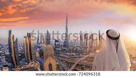 Arabian man watching cityscape of Dubai with modern futuristic architecture in United Arab Emirates.