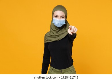 Arabian muslim woman in hijab green clothes sterile face mask to safe from coronavirus virus covid-19 pointing index finger on camera isolated on yellow background. People religious lifestyle concept - Powered by Shutterstock