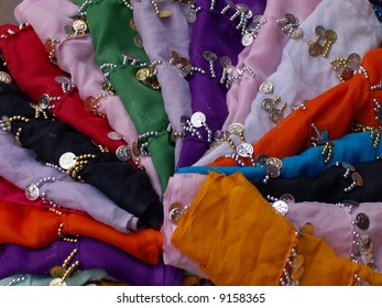 Arabian scarfs in the Market. Colorful fabrics interlaced with jewellery displayed in a circle.