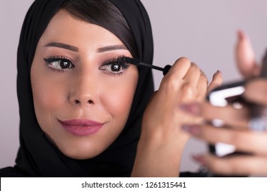 Arabic Beauty Model Girl Looking In The Mirror And Applying Mascara Make Up. Beautiful Arabic Woman Apply Makeup.
Arab Cosmetics Concept.