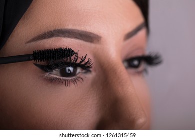 Arabic Beauty Model Girl Looking In The Mirror And Applying Mascara Make Up. Beautiful Arabic Woman Apply Makeup.
Arab Cosmetics Concept.