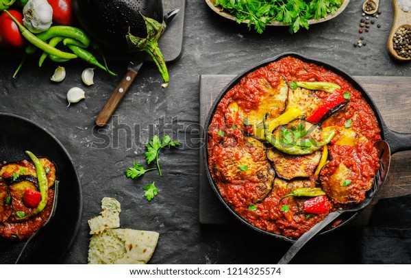 Arabic cuisine; Egyptian traditional food\
Moussaka. It contains fried eggplant(aubergine),colored bell\
peppers,chill peppers and garlic tomato sauce.Served with pita\
bread. Top view with\
close-up.