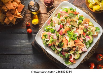 Arabic cuisine; Lebanon's most famous salad "Fattoush". It's juicy crunchy mix of cucumber, tomatoes, radish, toasted pita bread, fresh mint and parsley. Close up with copy space. - Shutterstock ID 1666896364