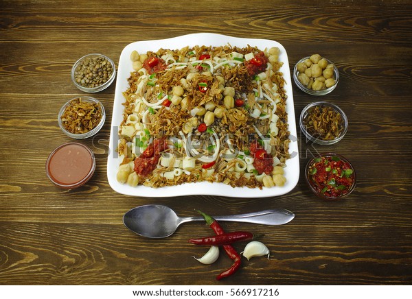 Arabic cuisine, Traditional\
Egyptian food:Delicious Kushary of\
rice,pasta,chickpeas,lentils,crispy onions and tomato sauce on a\
plate..Top view,Close\
up..