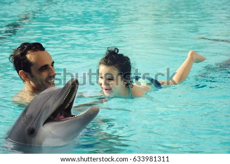 Arabic dad with his baby enjoying the swimming pool, dolphin