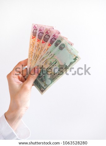 Arabic dirhams in hand.