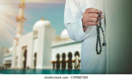 Arabic man hand holding a muslim rosary standing front a mosque. ramadan holy month, Ramadhan kareem concept.