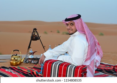 Arabic Man From Saudi Arabia Sitting In The Desert And Wears Traditional Clothes