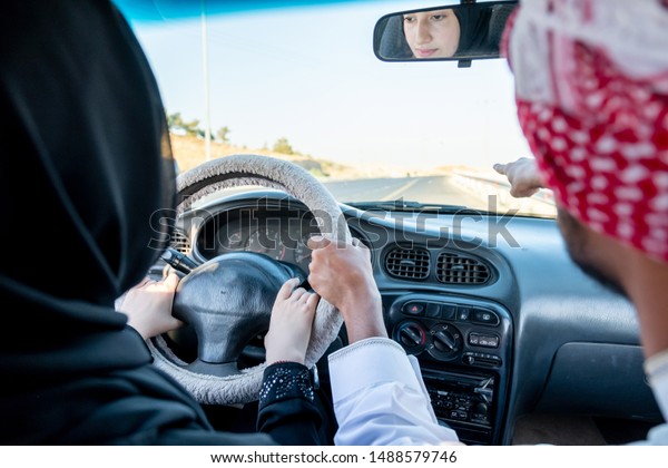 Arabic man teaching\
arabic woman driving