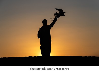 Arabic man in traditional clothing with a falcon, UAE ABUDHABI LIWA - Powered by Shutterstock