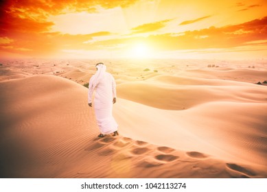 Arabic man with traditional emirates clothes walking in the desert - Powered by Shutterstock