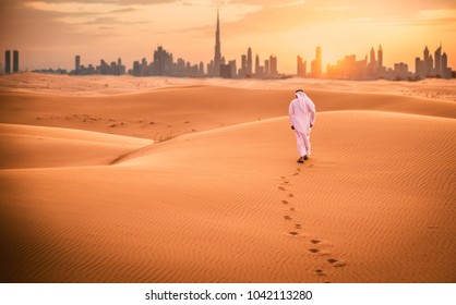 Arabic man with traditional emirates clothes walking in the desert - Shutterstock ID 1042113280
