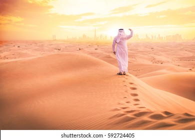 Arabic Man With Traditional Emirates Clothes Walking In The Desert