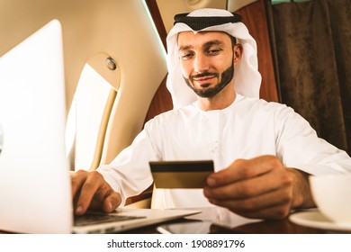 Arabic man wearing kandora in emirates style flying on exclusive private jet - Middle-eastern businessman with traditional dress flies in exclusive business class on airplane