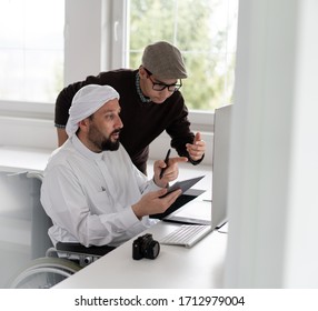 Arabic man in wheelchair at desk with computer