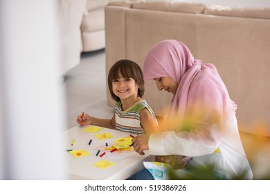 Arabic mother with little son in living room watering flowers - Shutterstock ID 519386926